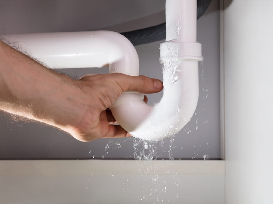 A Man's Hand Holding The Leakage White Sink Pipe In Kitchen in Bathurst, NSW