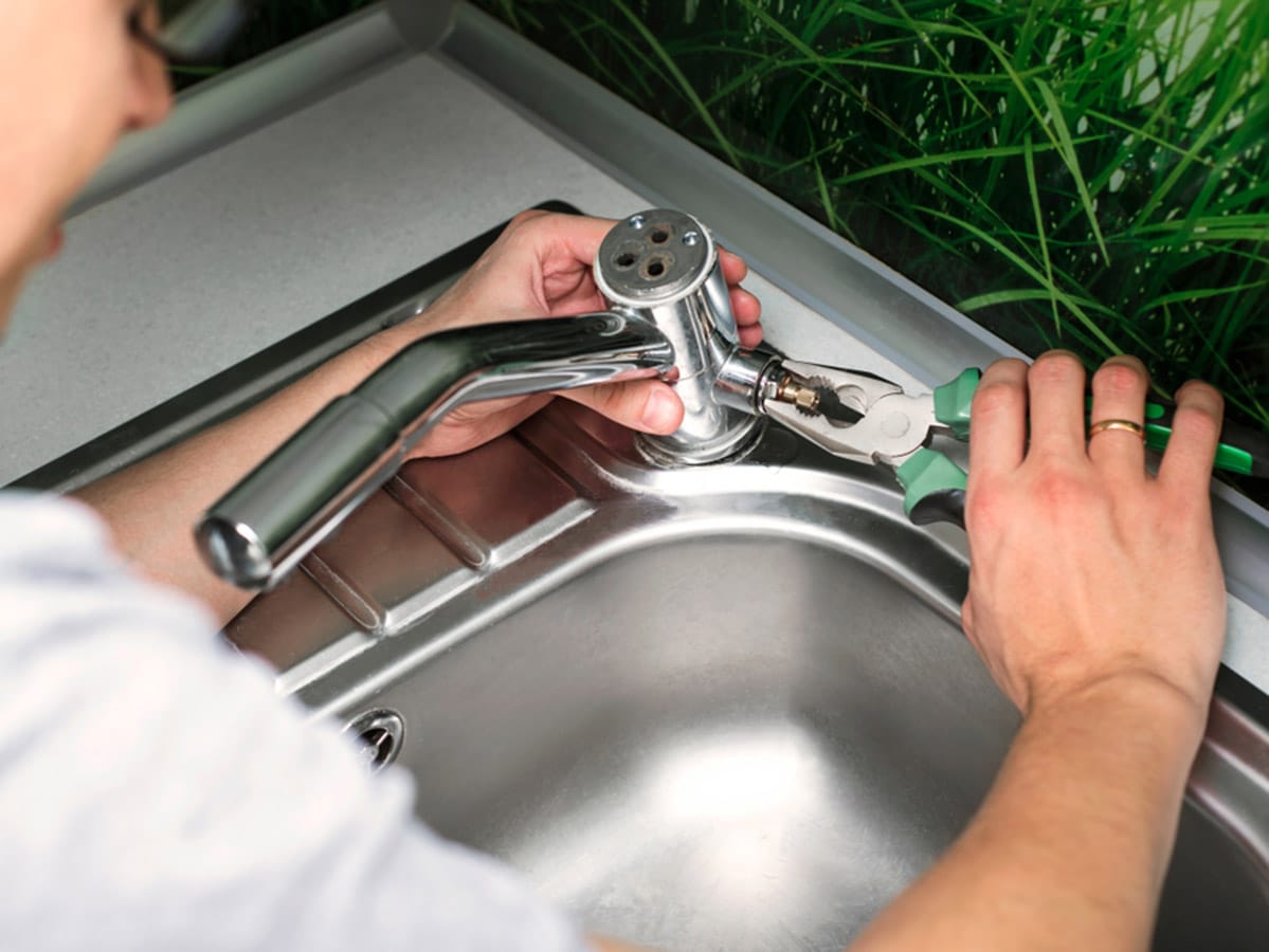 Plumber Repairing the Faucet of a Sink in the Kitchen in Bathurst, NSW