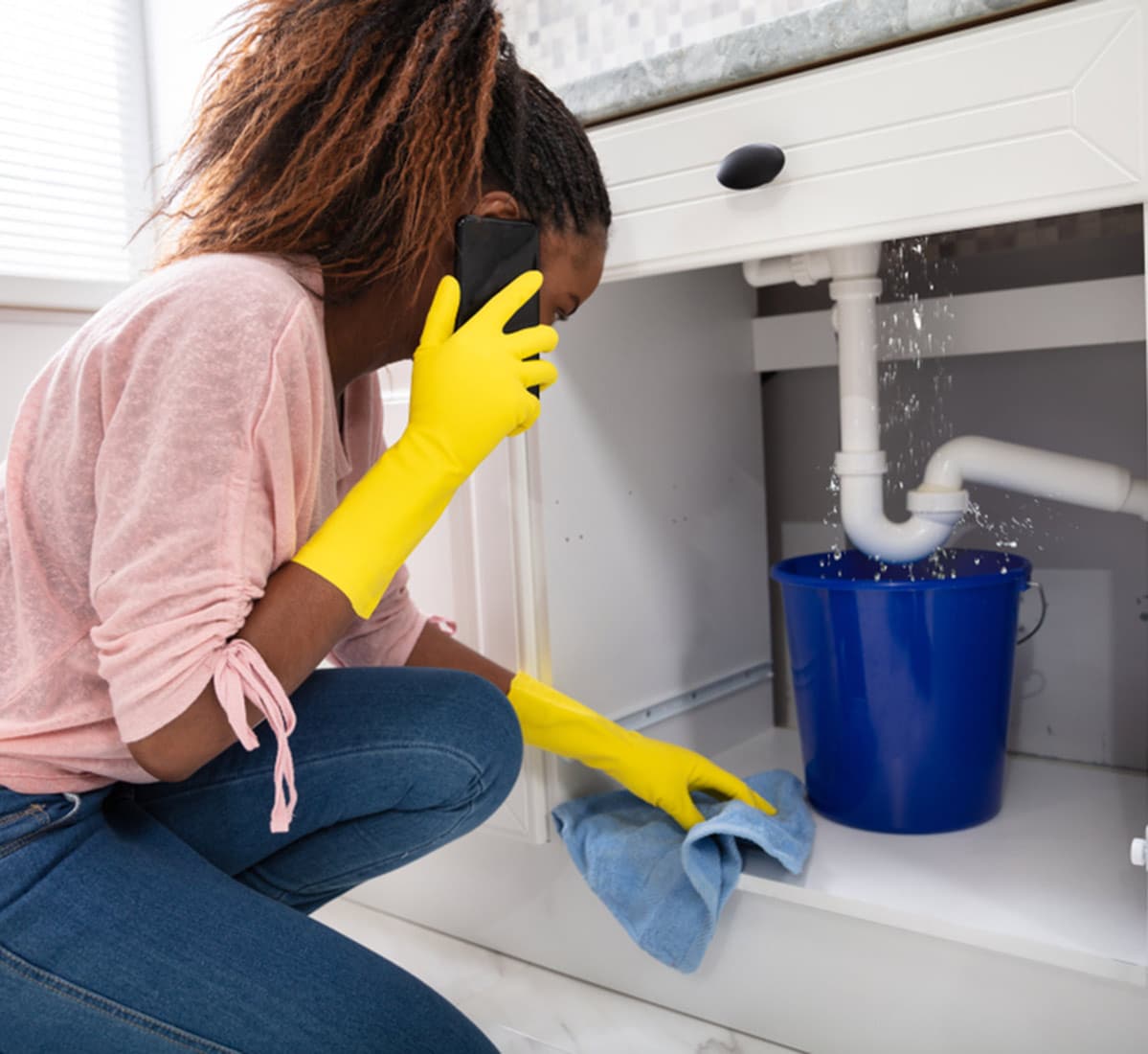 A Young Woman Placing Blue Bucket Under Leaking Sink Pipe in Bathurst, NSW