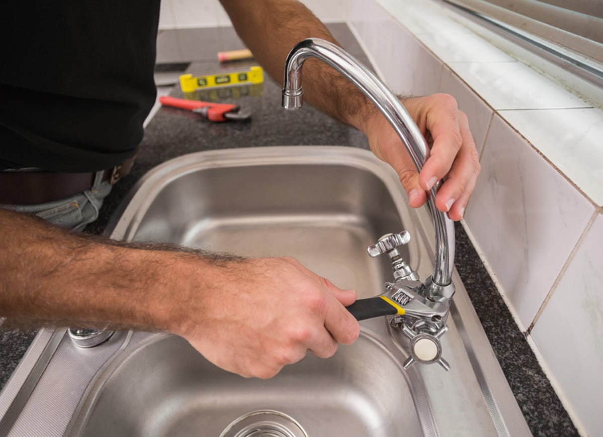 Plumber Fixing the Sink With Wrench in the Kitchen - Plumbing Services In Lithgow, NSW