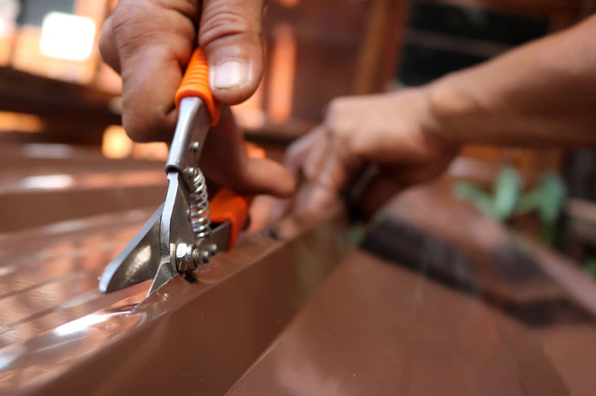 A Worker Use Scissors to Cut the Metal Sheet for Roofing - Roofing and Guttering Services in Oberon, NSW