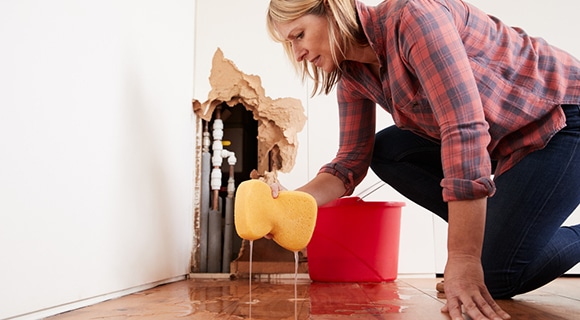 Worried Woman Mopping Up Water From a Burst Pipe in Bathurst, NSW