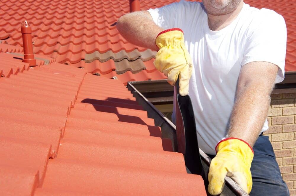 Worker With Yellow Gloves Working On The Roof - Roofing and Guttering Services in Orange, NSW