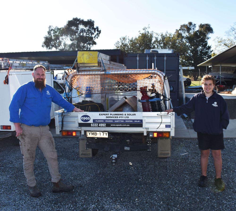 Two plumbers beside a work truck